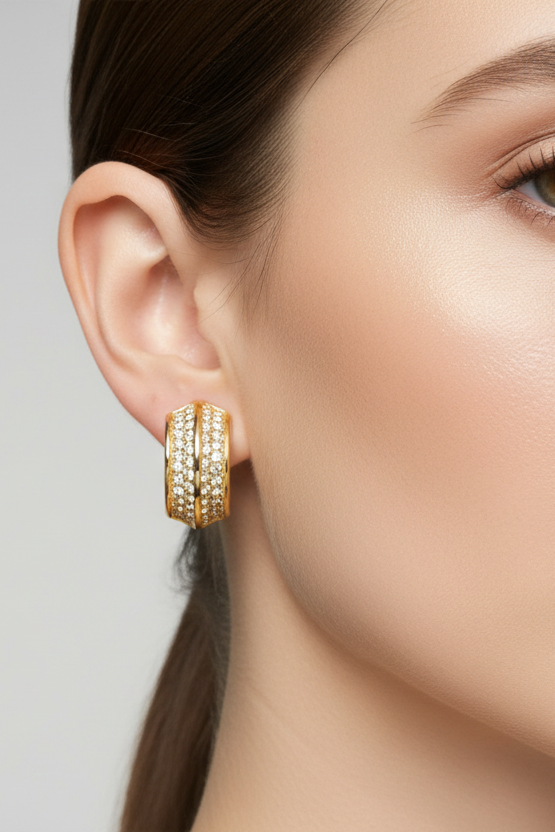 Gold hoop earrings worn by a model on a neutral background
