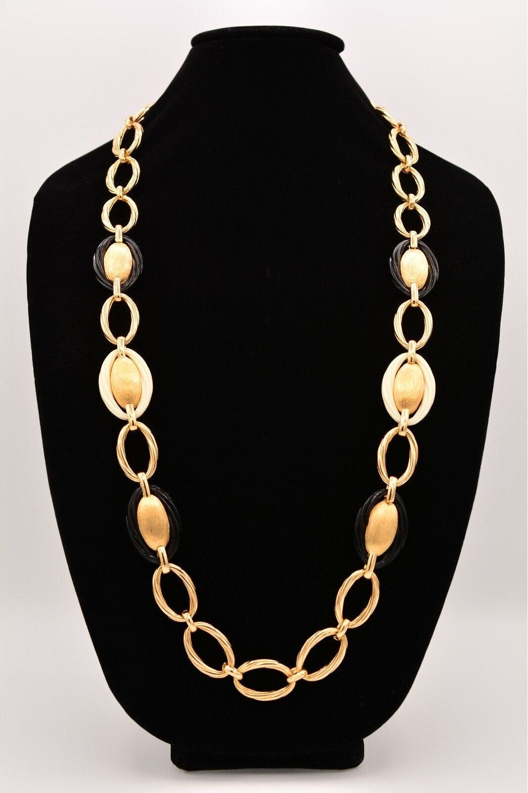 Gold chain necklace on a black mannequin bust against a white background