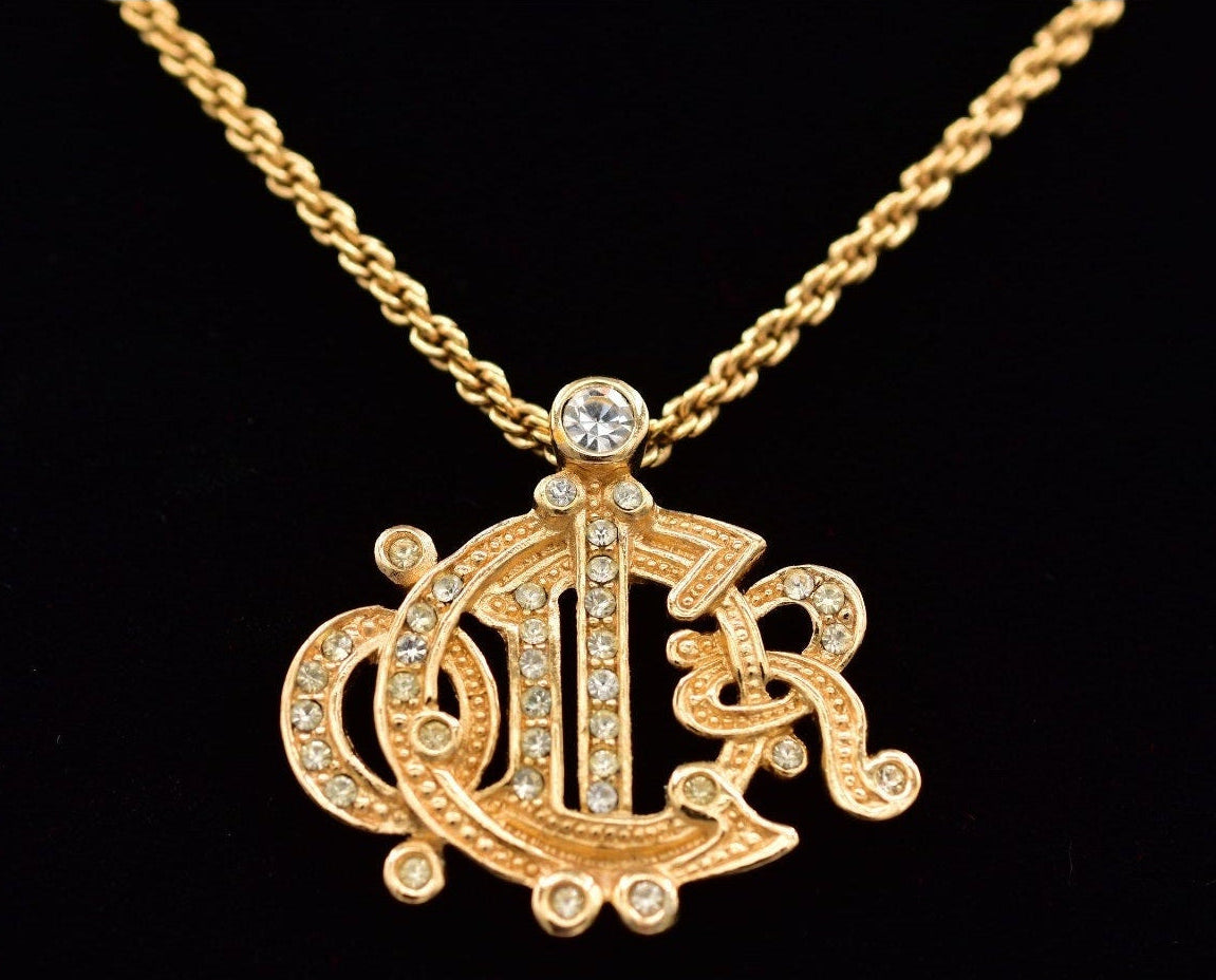 Vintage Christian Dior monogram pendant necklace with a decorative rhinestones on a black background