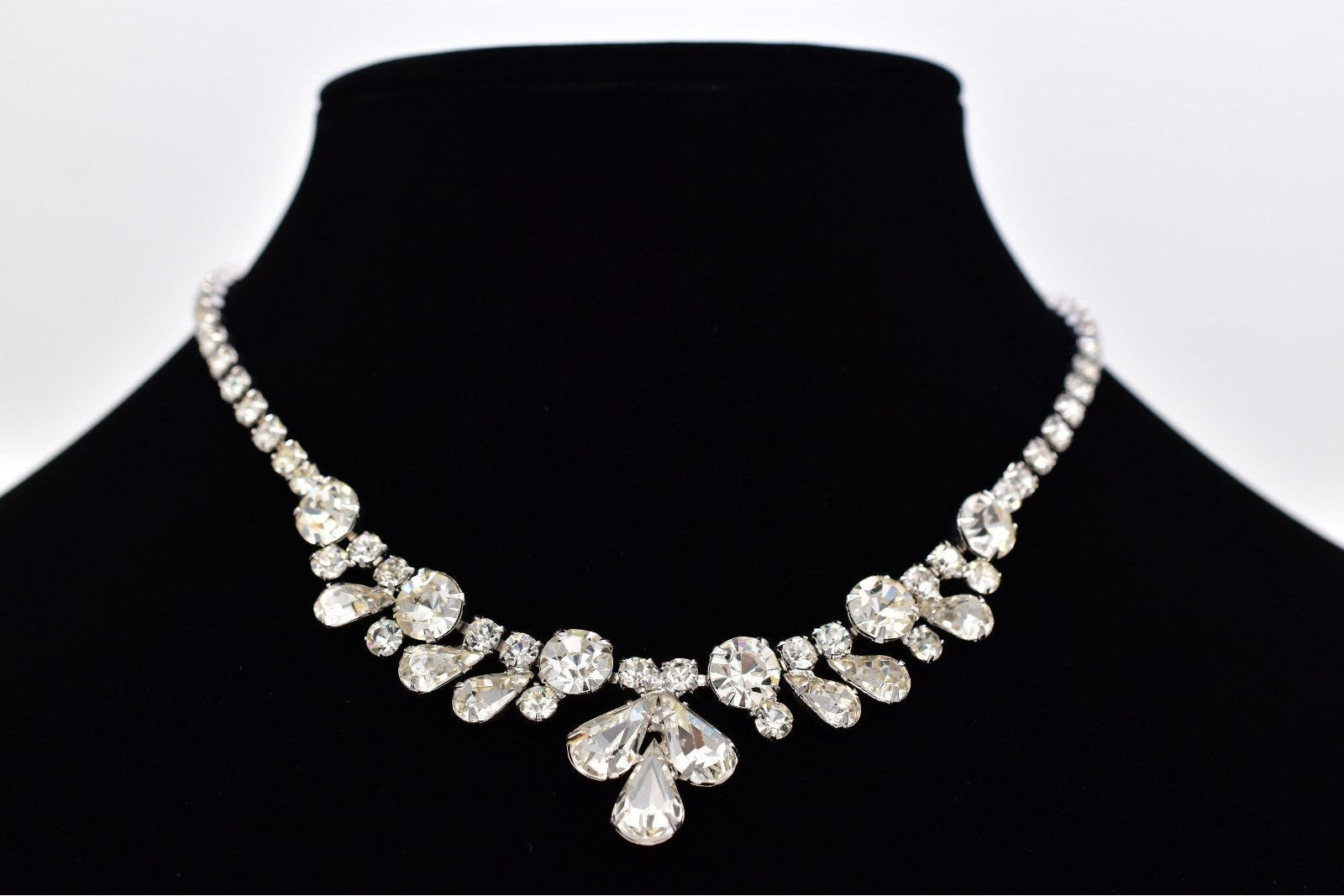 Silver necklace on a black mannequin against a white background