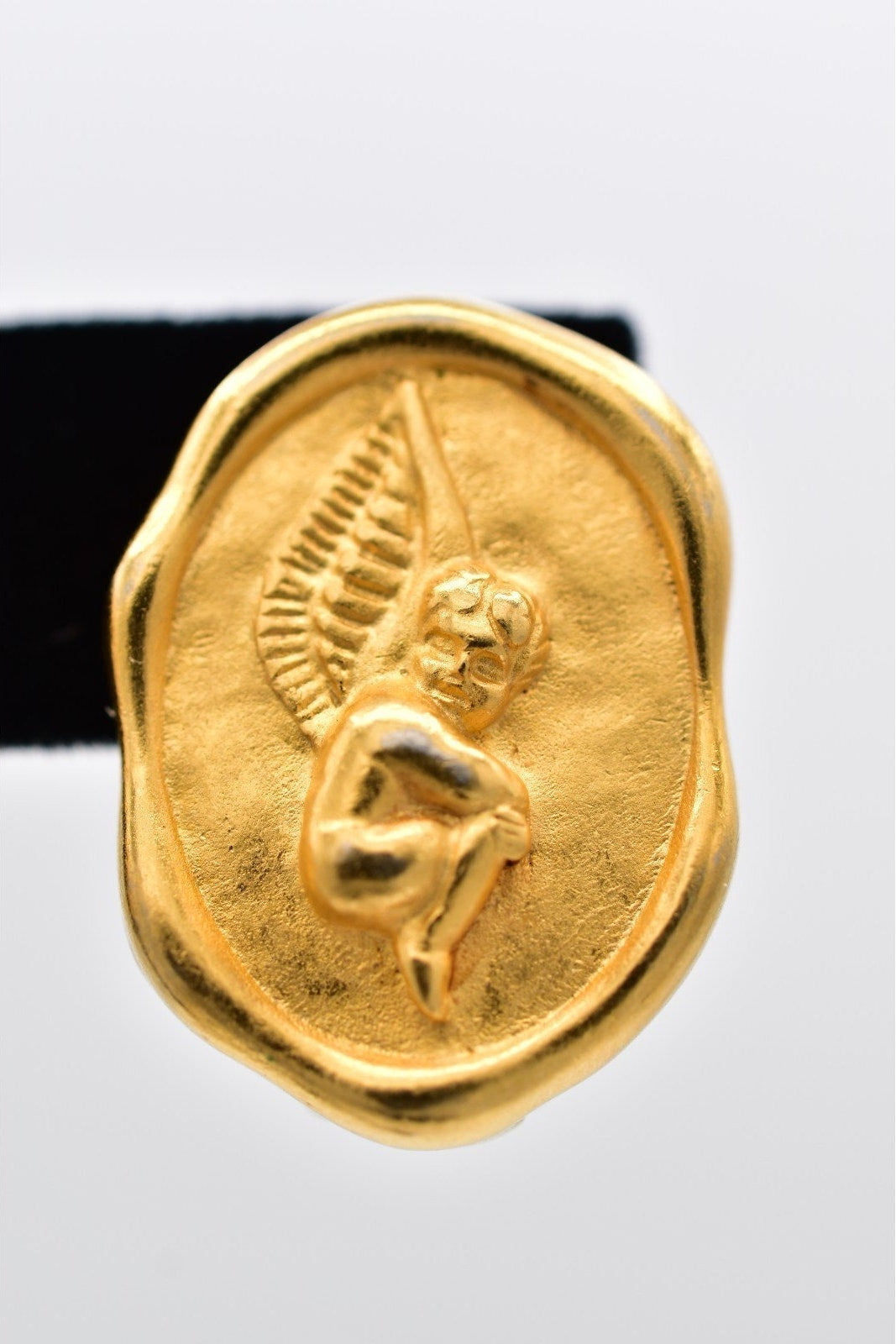 Gold ring with a winged figure design on a white background