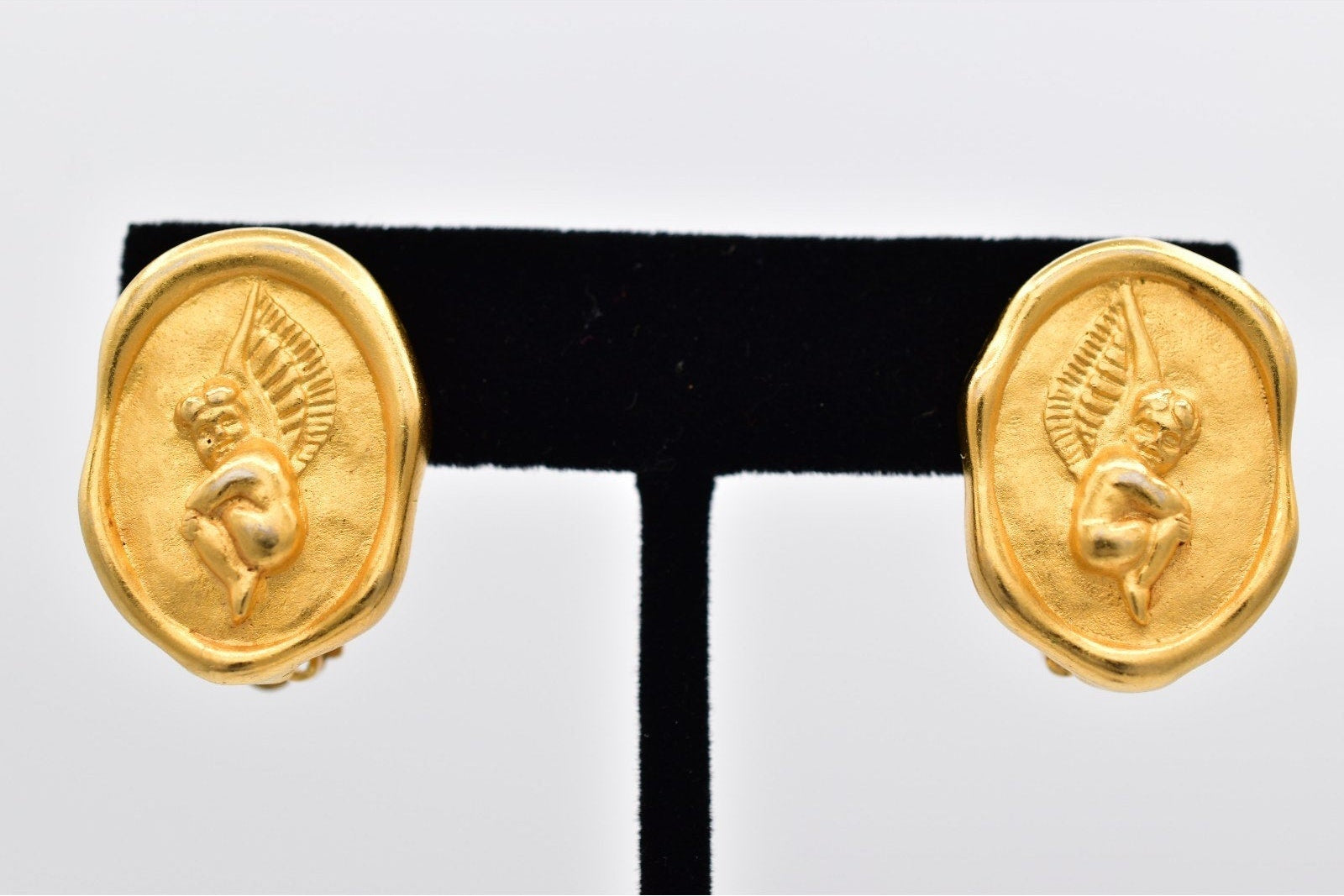 Pair of gold earrings on a black and white display stand.