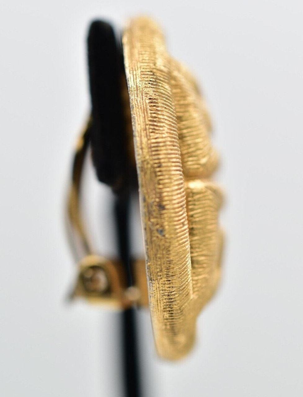 Gold-colored earring on a light gray background