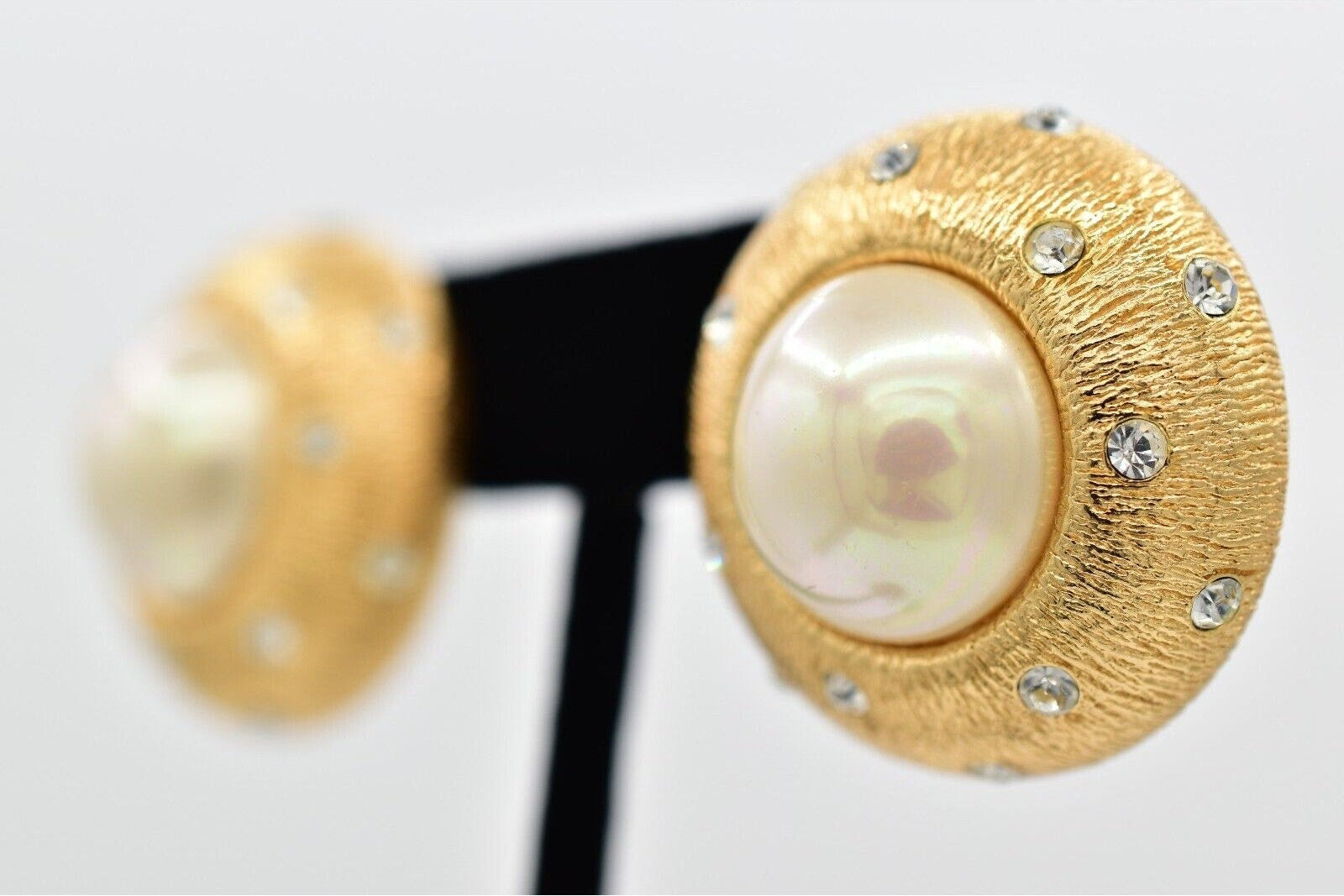 Gold earrings with pearls and small crystals on a white background