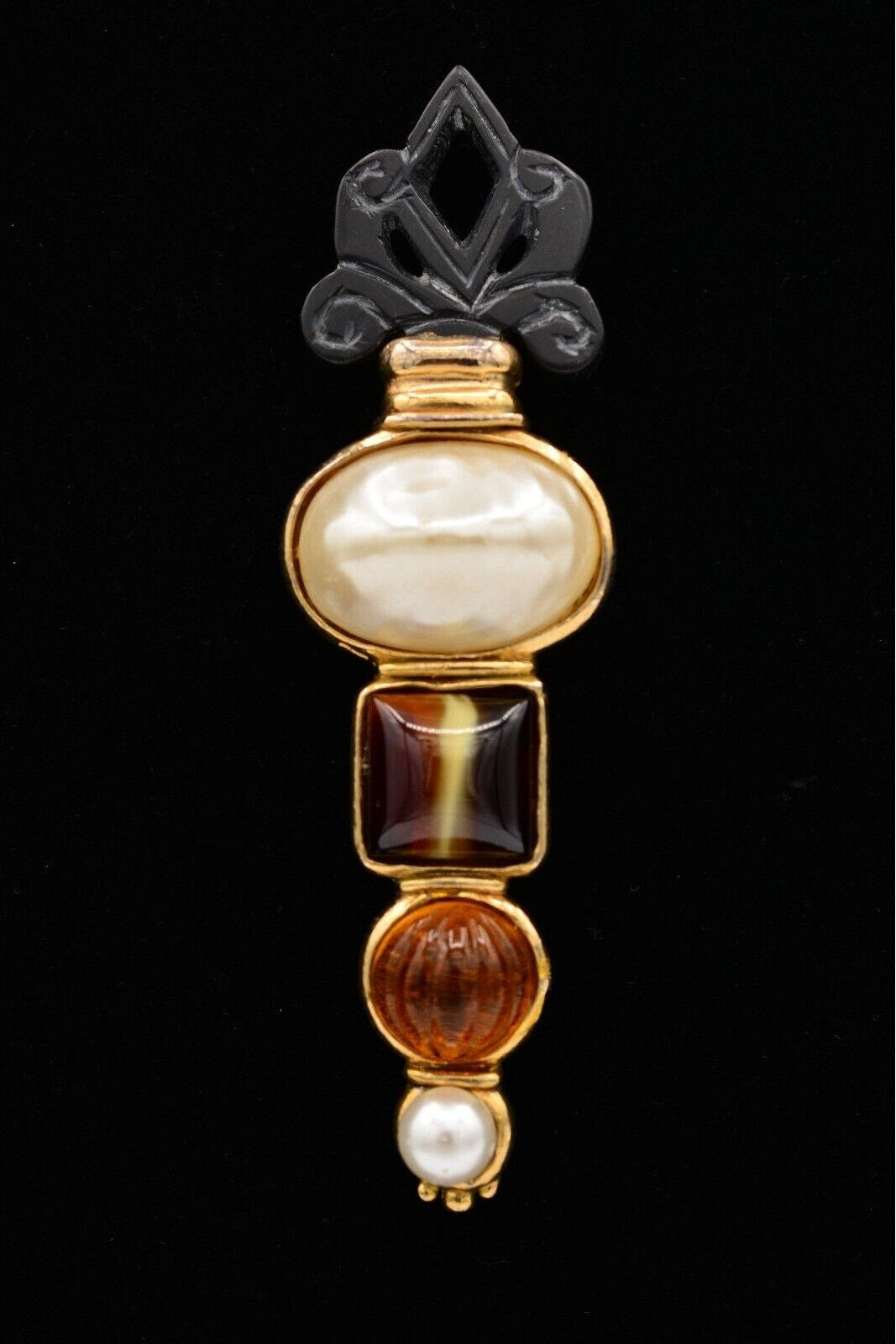 Decorative brooch with pearls and gemstones on a black background