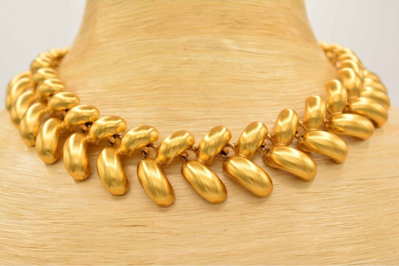 Gold necklace on a mannequin with a plain background