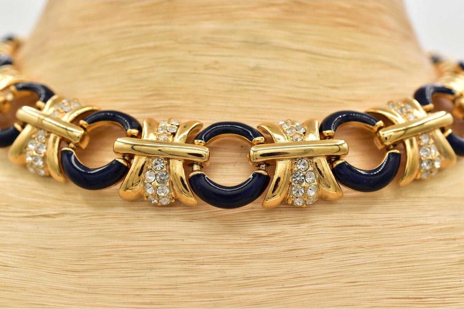 Gold and black bracelet with rhinestone accents on a straw surface
