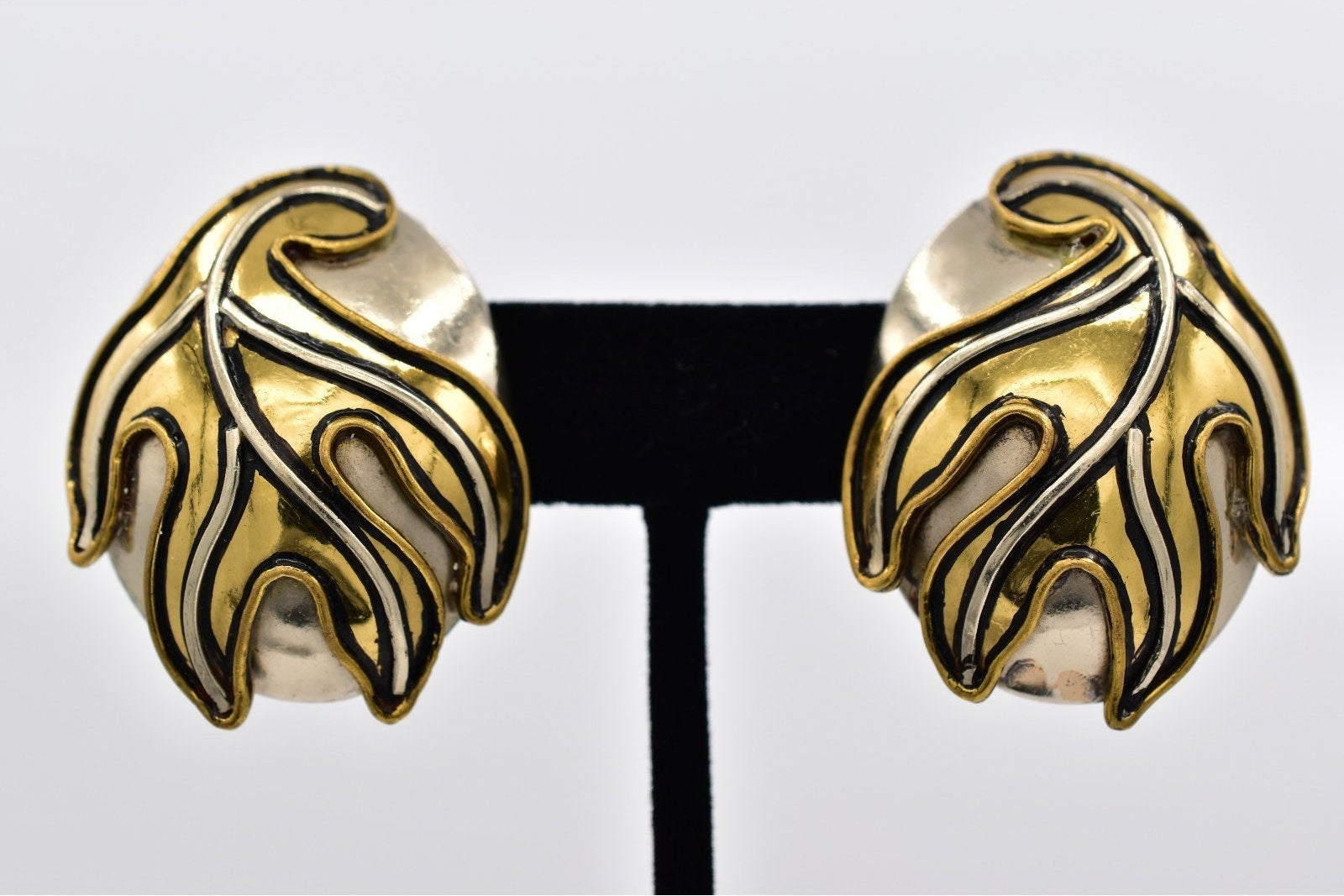 Gold and silver leaf-shaped earrings on a white background