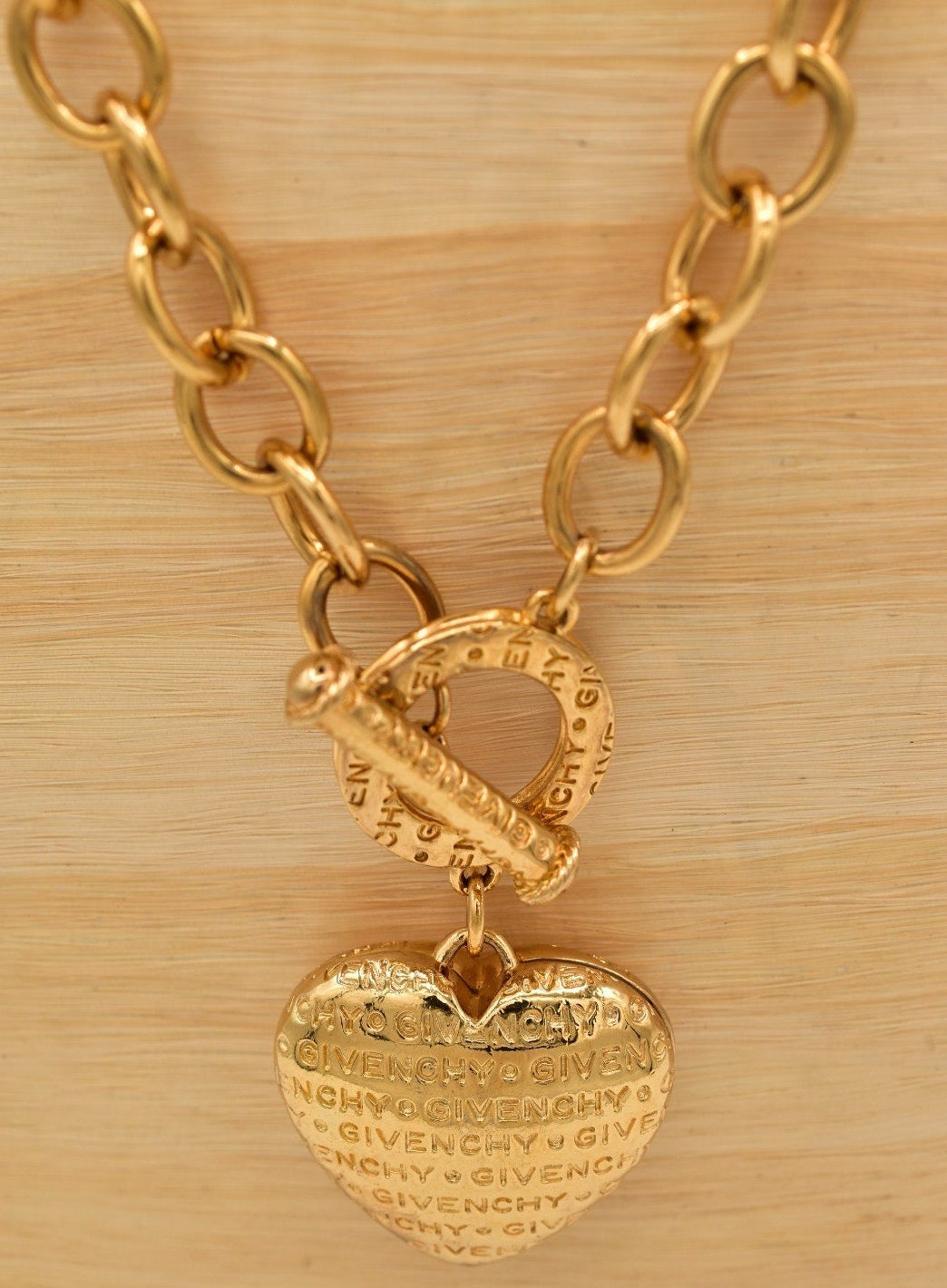 Gold chain necklace with a heart-shaped pendant on a wooden surface