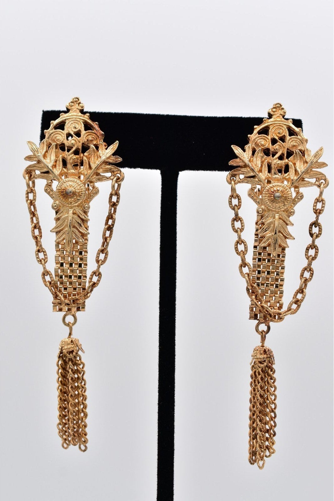 Pair of gold earrings with intricate designs on a white background