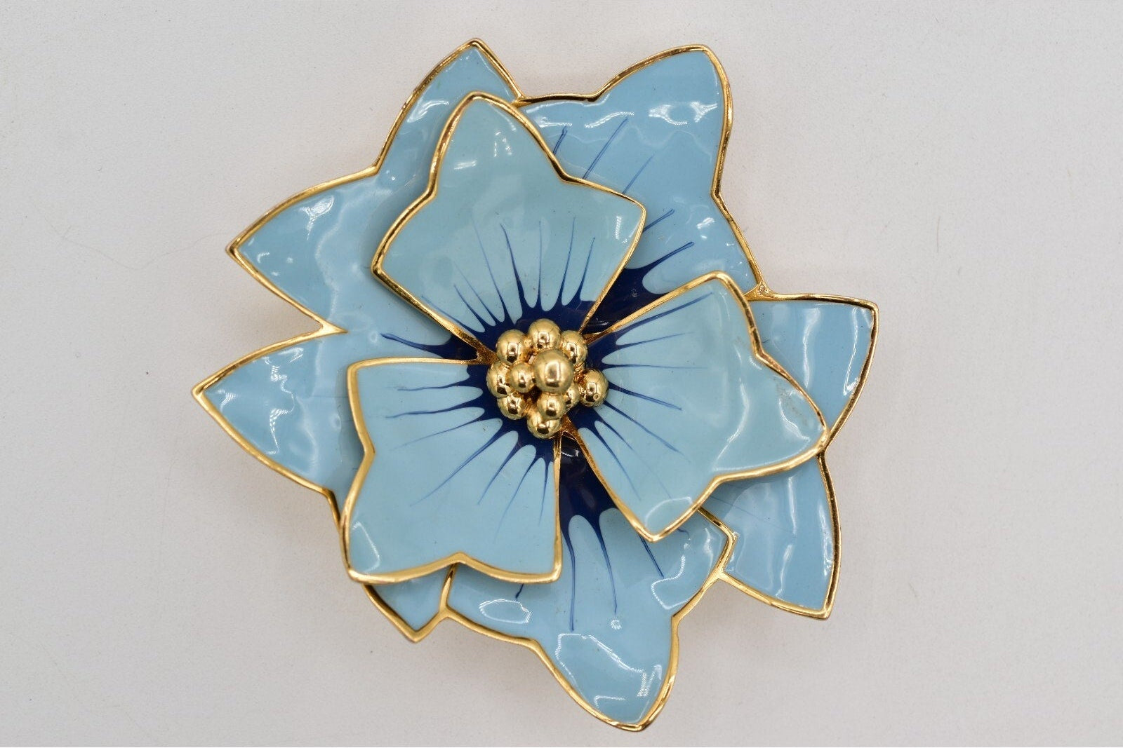 Blue flower-shaped object with gold accents on a light gray background