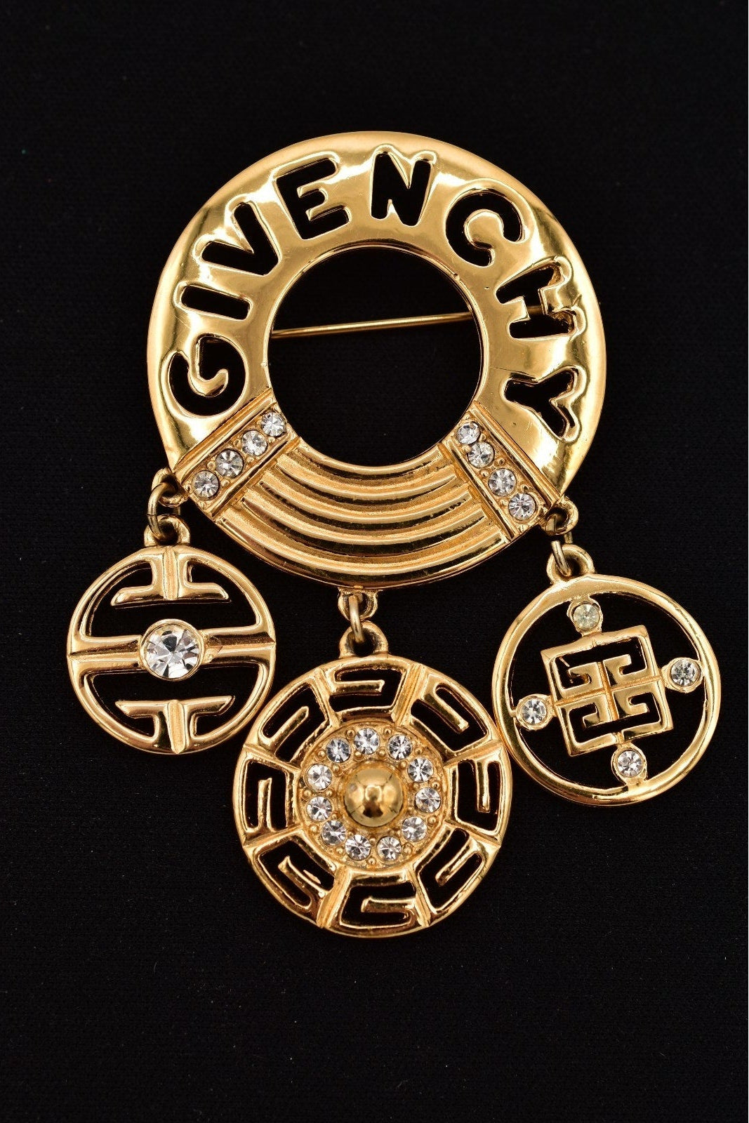 Gold Givenchy brooch with intricate designs and crystals on a black background