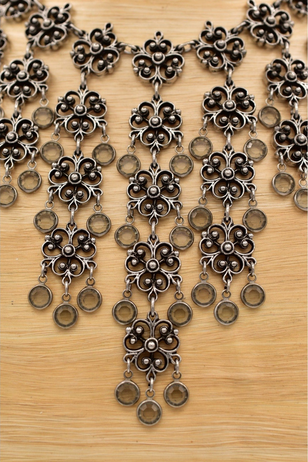 Decorative necklace with floral and circular patterns on a wooden surface