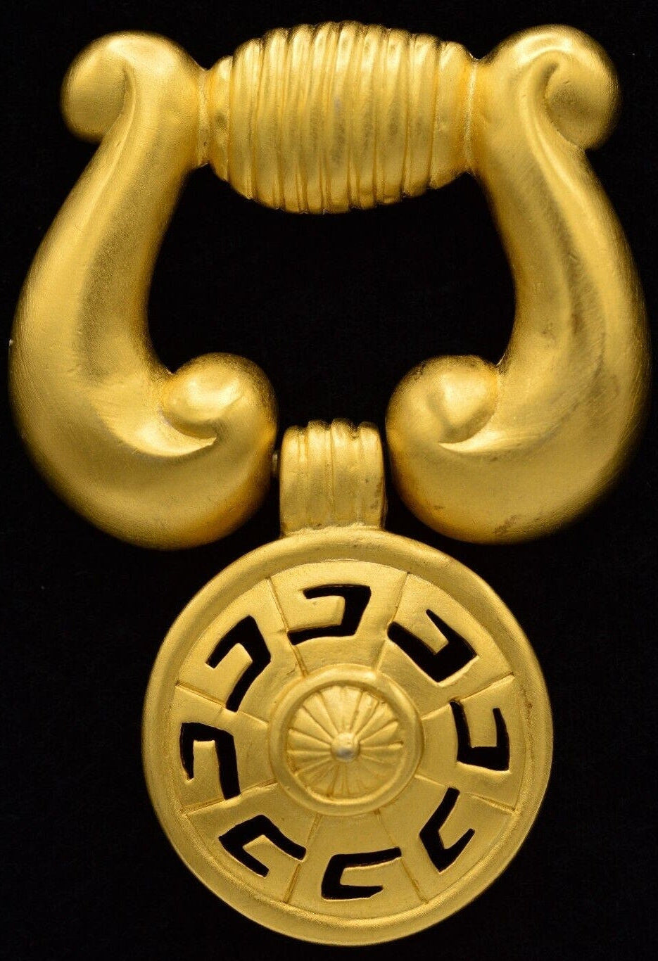 Gold decorative element with a circular design on a black background