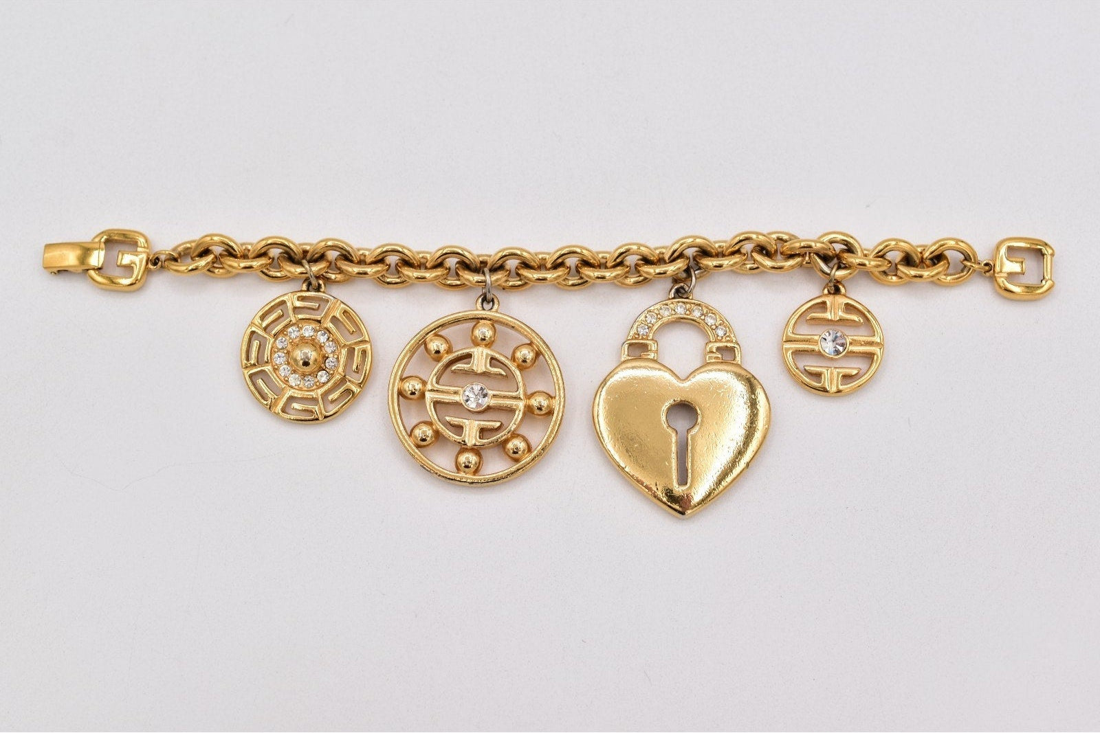 Gold bracelet with four charms on a light gray background