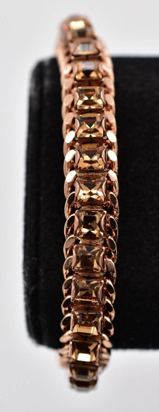 Rose gold hoop earring on a black stand against a light gray background