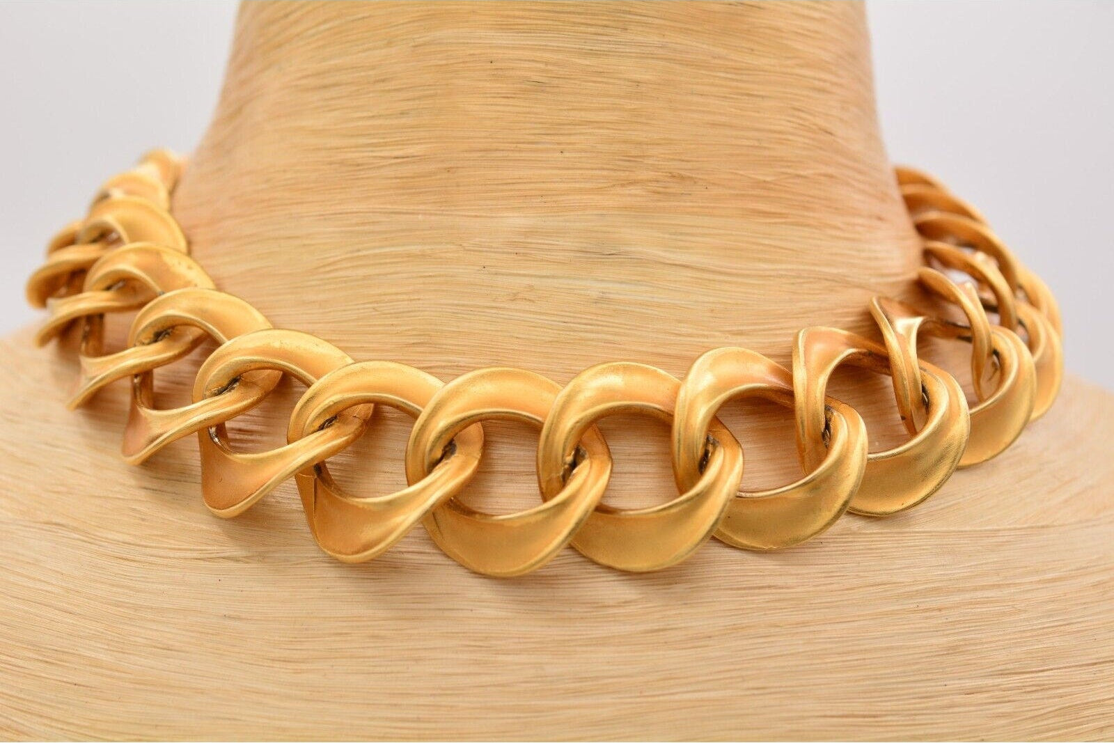 Gold chain necklace on a mannequin head with a plain background