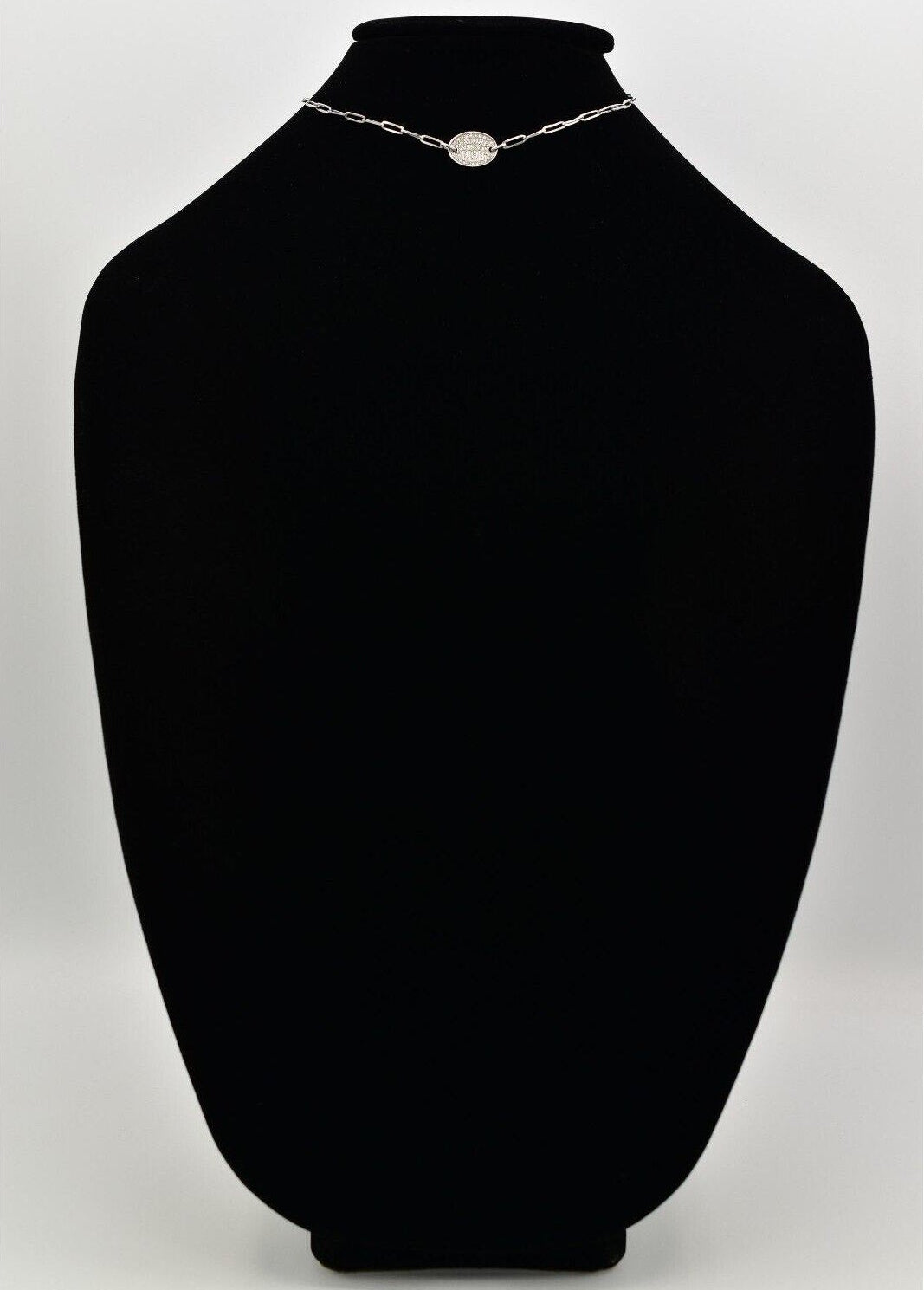 Black mannequin bust with a vintage Dior J'Adore silver chain necklace and a round pendant.