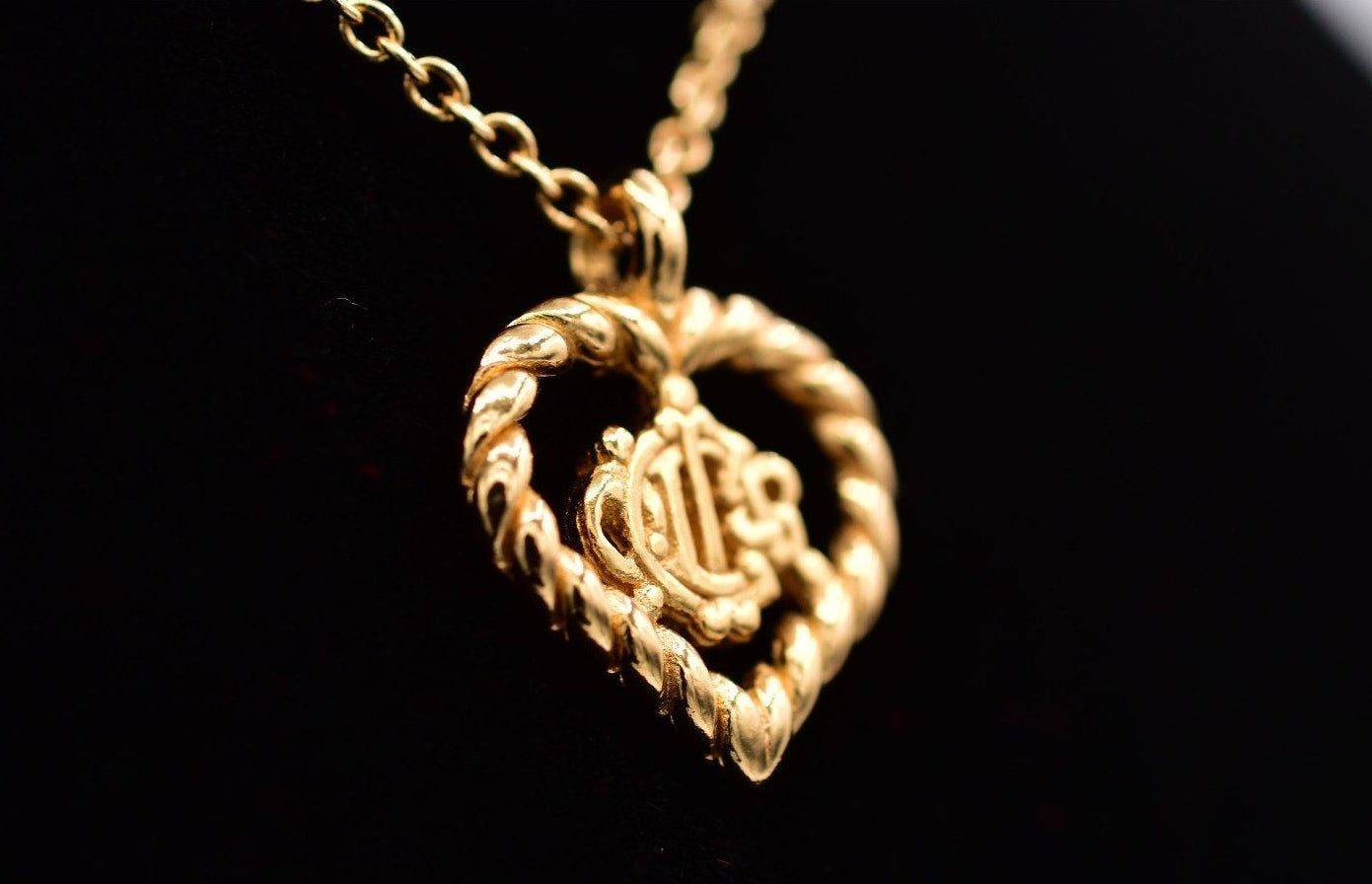 Gold heart-shaped necklace with a pendant on a black background