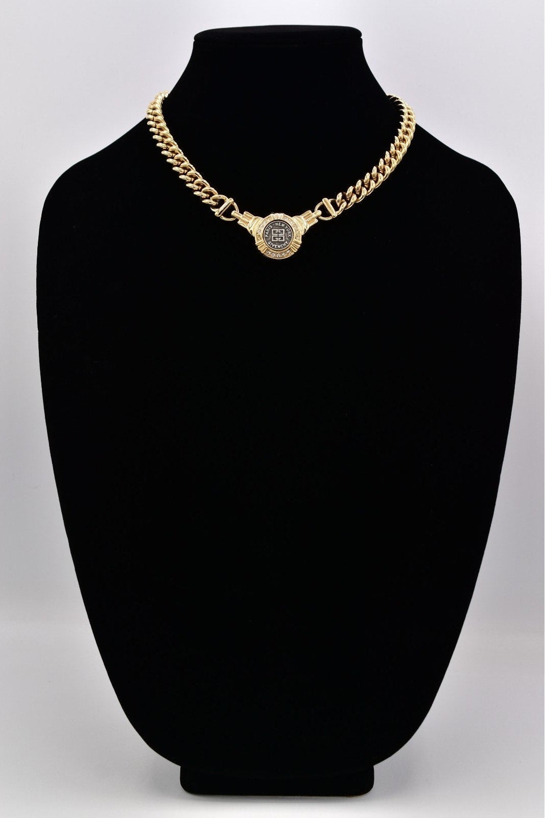 Gold chain necklace on a black mannequin bust against a white background