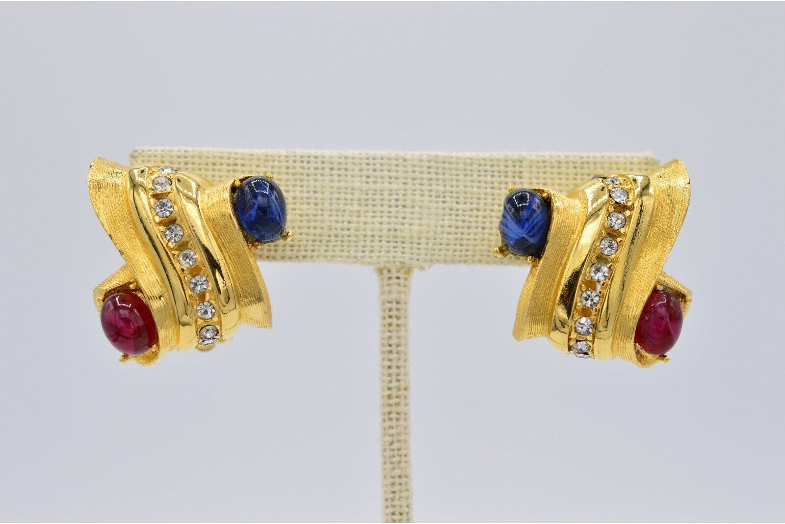 Pair of gold earrings with gemstones on a gray background