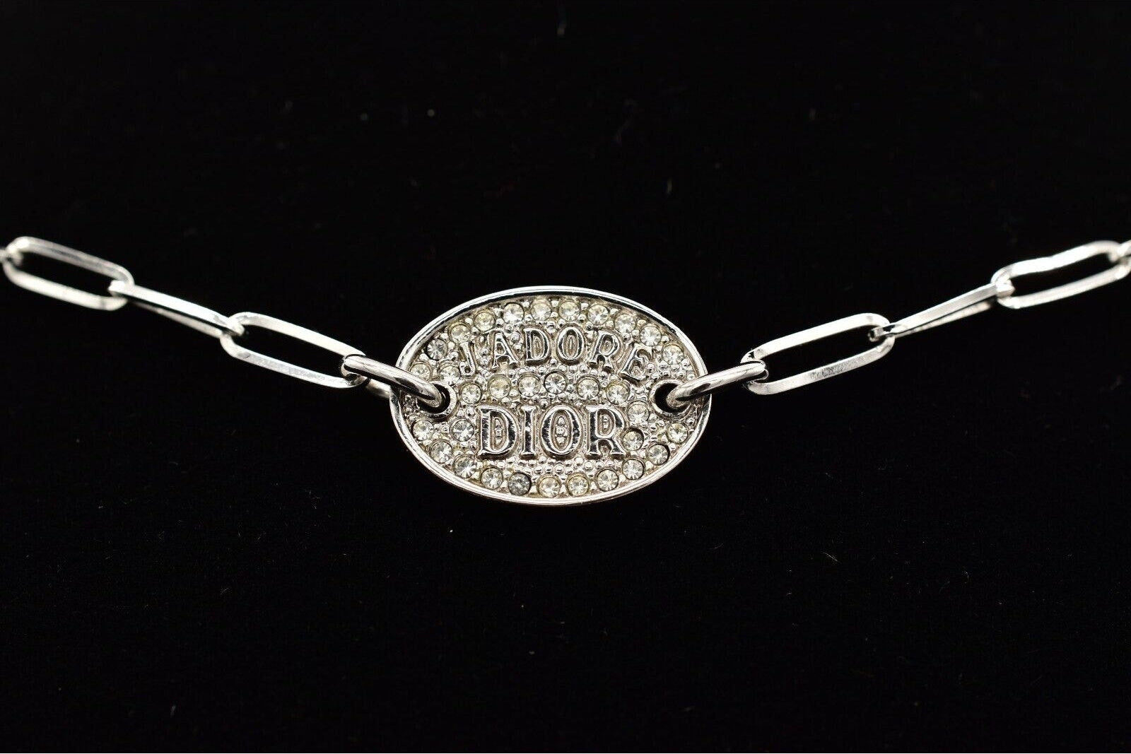 Silver chain bracelet with Dior plaque on a black background