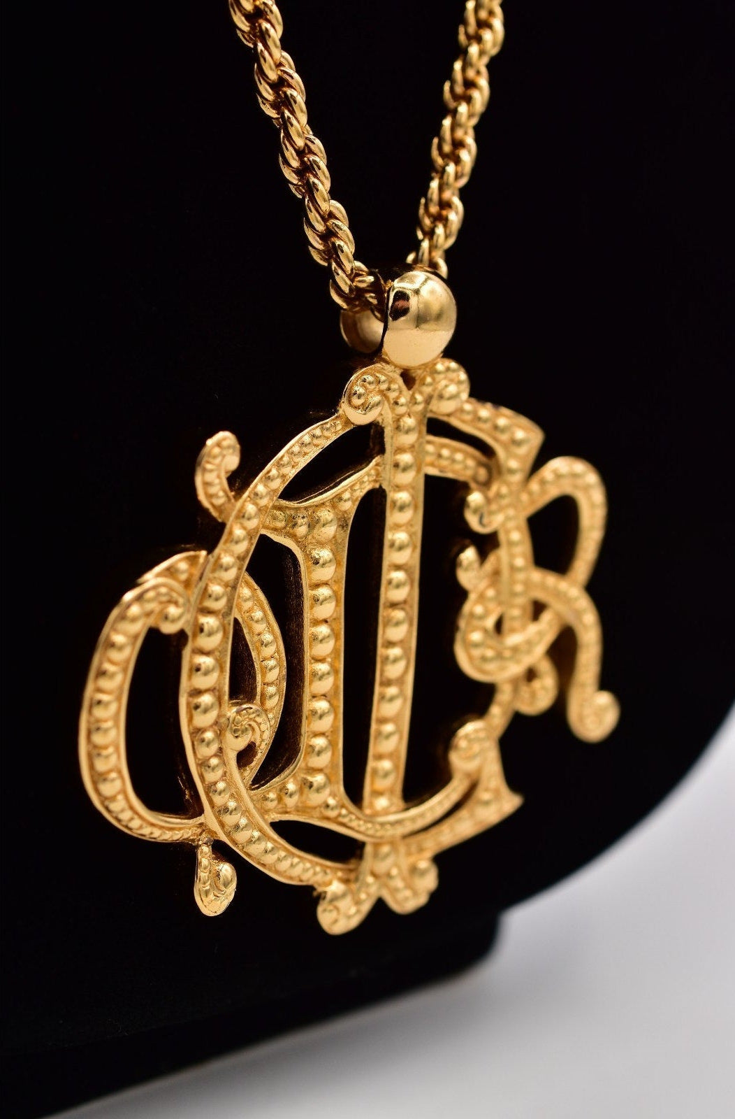 Gold necklace with an ornate pendant on a black background