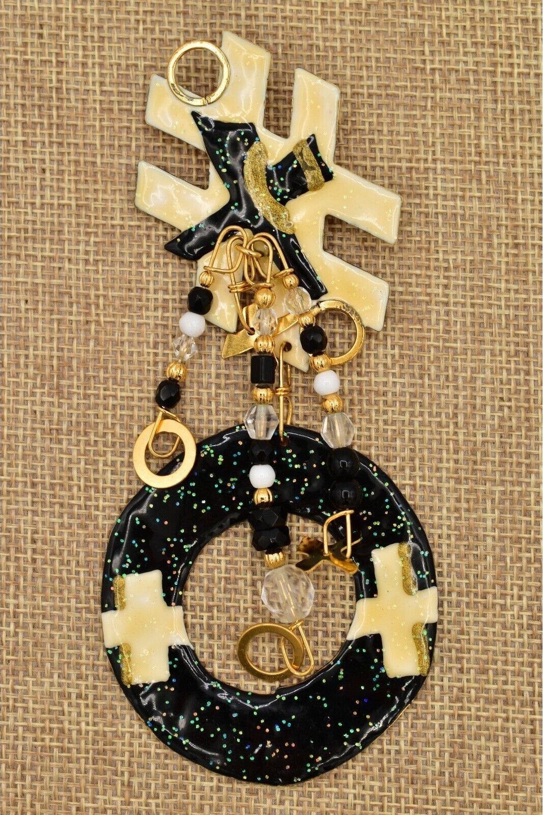 Vintage Tic Tac Toe brooch with black, gold, and white elements on a textured beige background