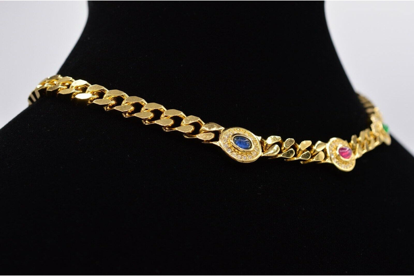 Gold chain bracelet with embedded stones on a black mannequin.