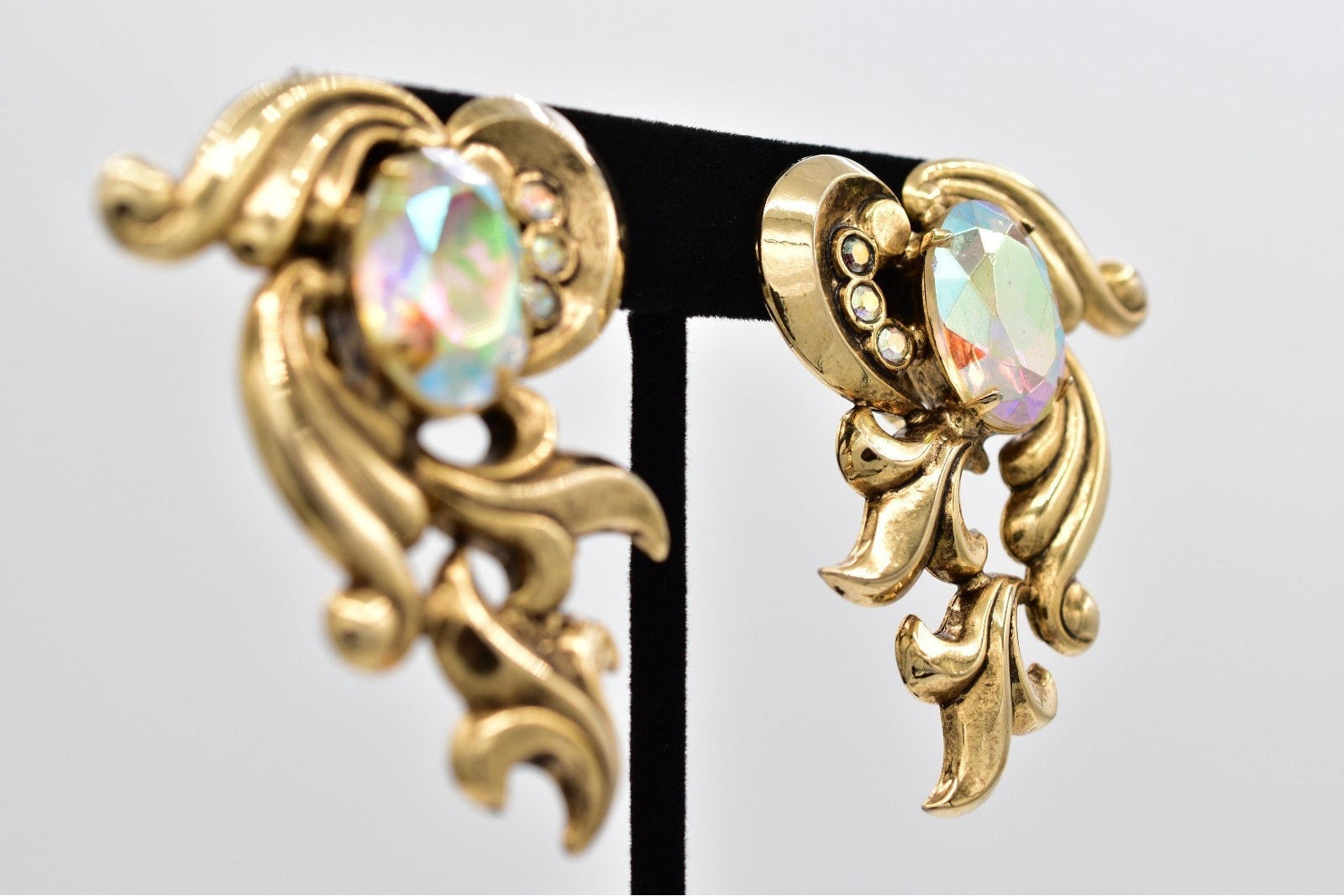 Gold earrings with opal-like gemstones on a gray background