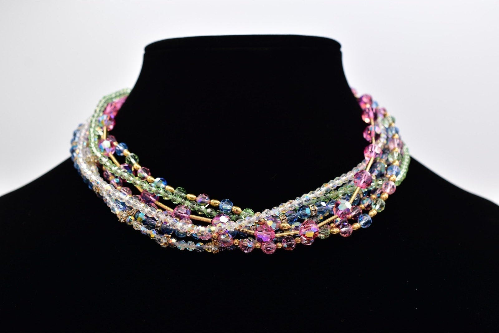 Multicolored beaded necklace on a black mannequin against a white background