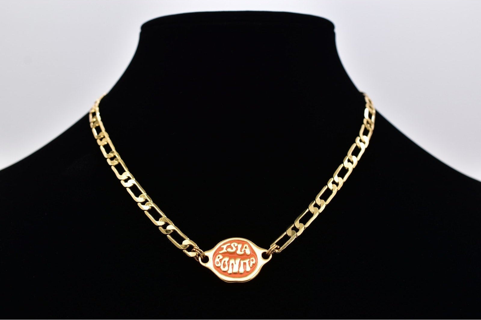 Gold chain necklace on a black mannequin with a white background