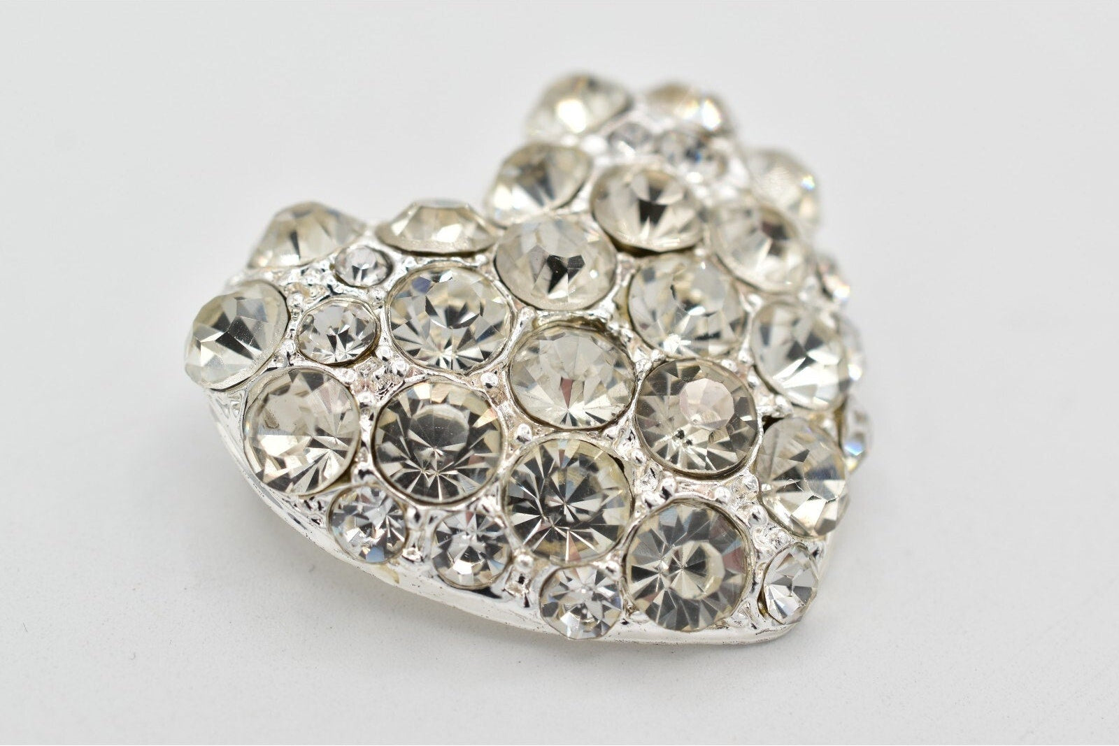 Heart-shaped decorative item with embedded crystals on a light gray background