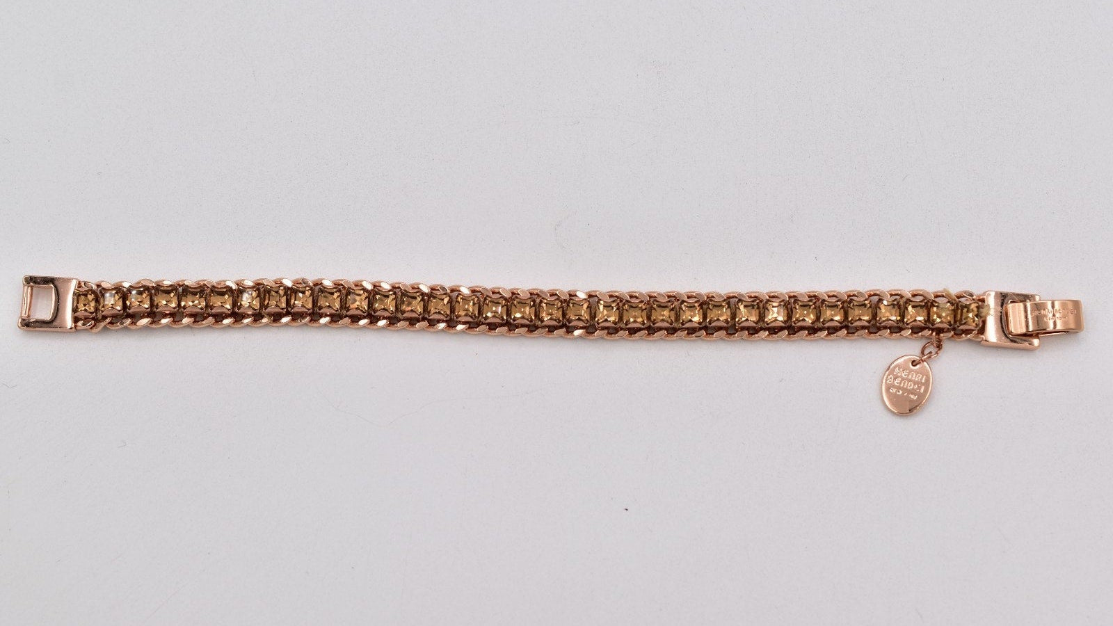 Rose gold bracelet with a heart charm on a light gray background