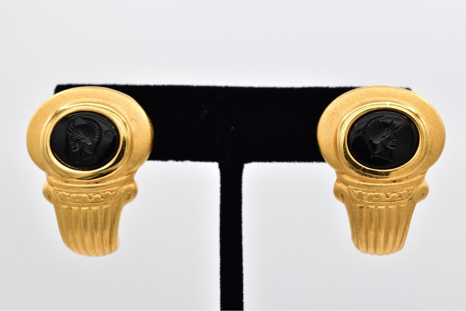 Gold earring with black gemstones on a white background