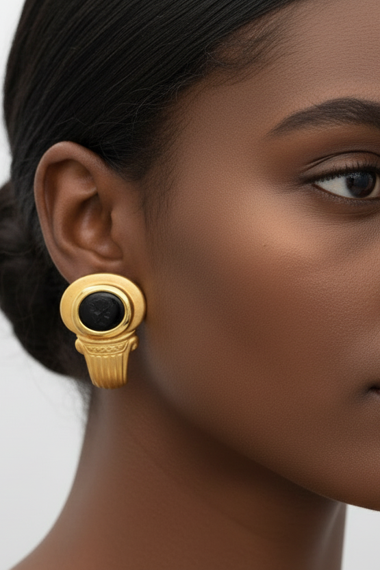 Gold earring with black gemstones on a white background