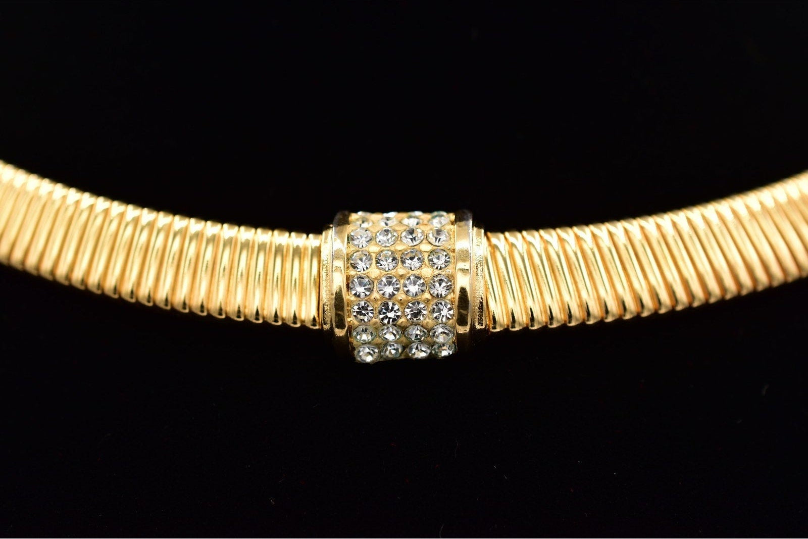 Gold necklace with a decorative clasp on a black background