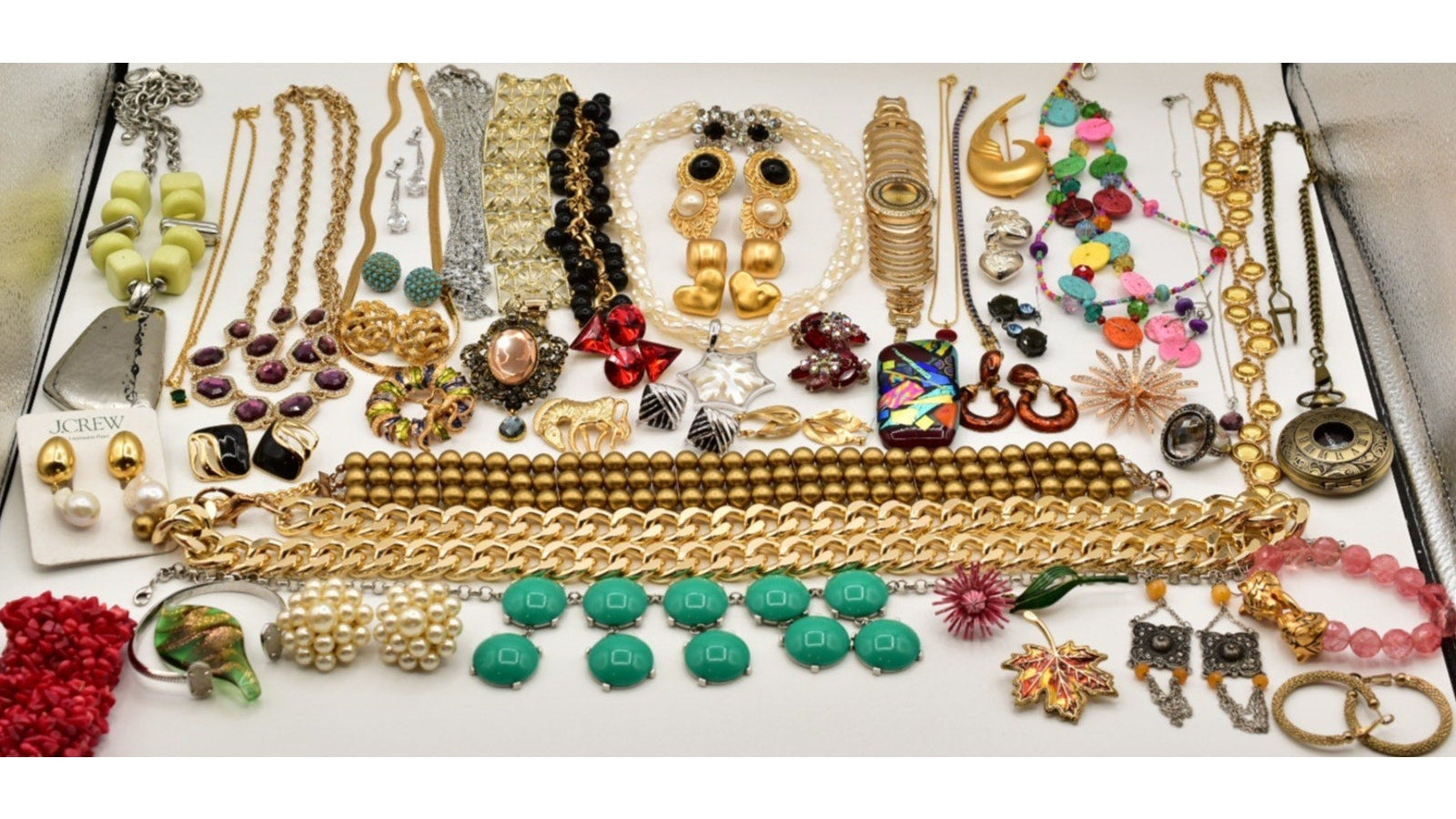 Assorted jewelry including necklaces, earrings, and bracelets on a white surface.