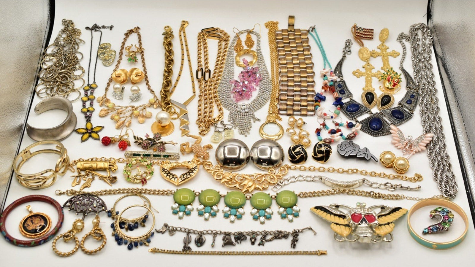 Assorted jewelry including necklaces, bracelets, and rings on a white surface.