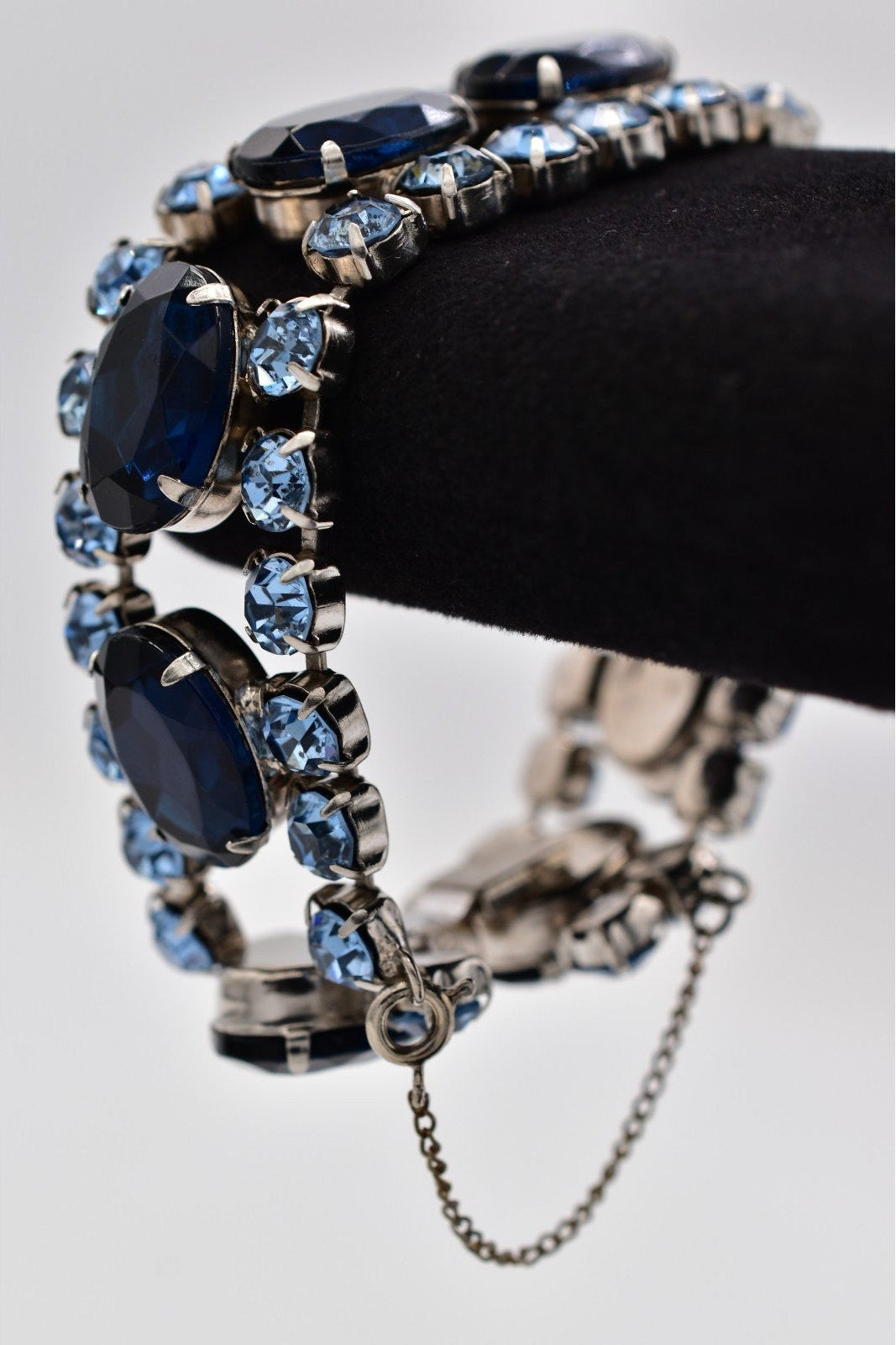 Bracelet with blue gemstones on a black mannequin hand against a white background