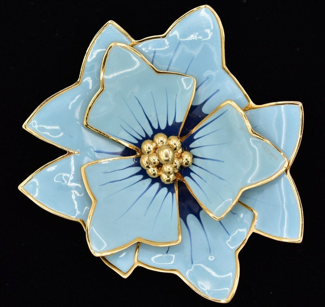 Blue flower-shaped brooch with gold accents on a black background
