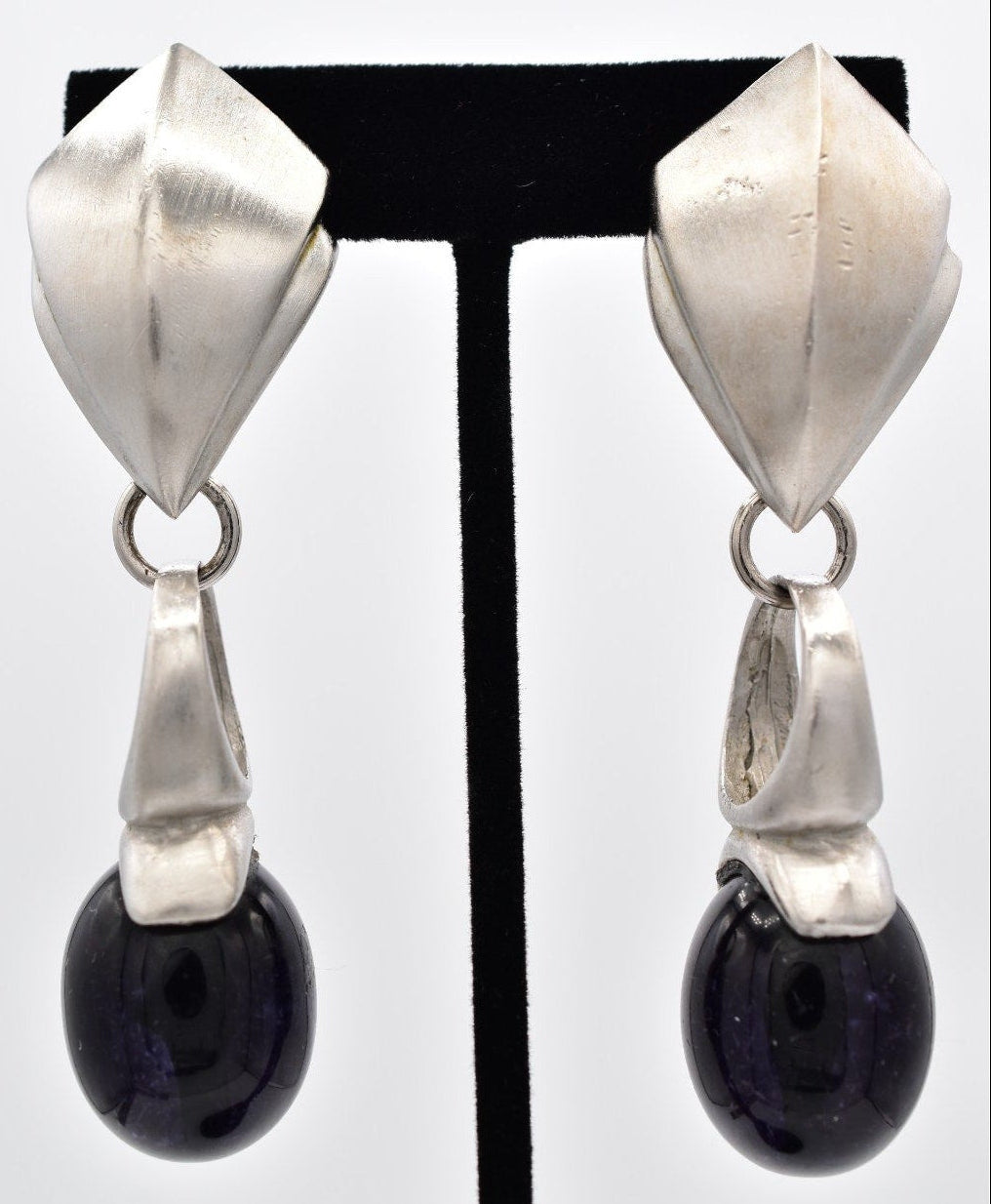 Pair of silver earrings with black beads on a white background