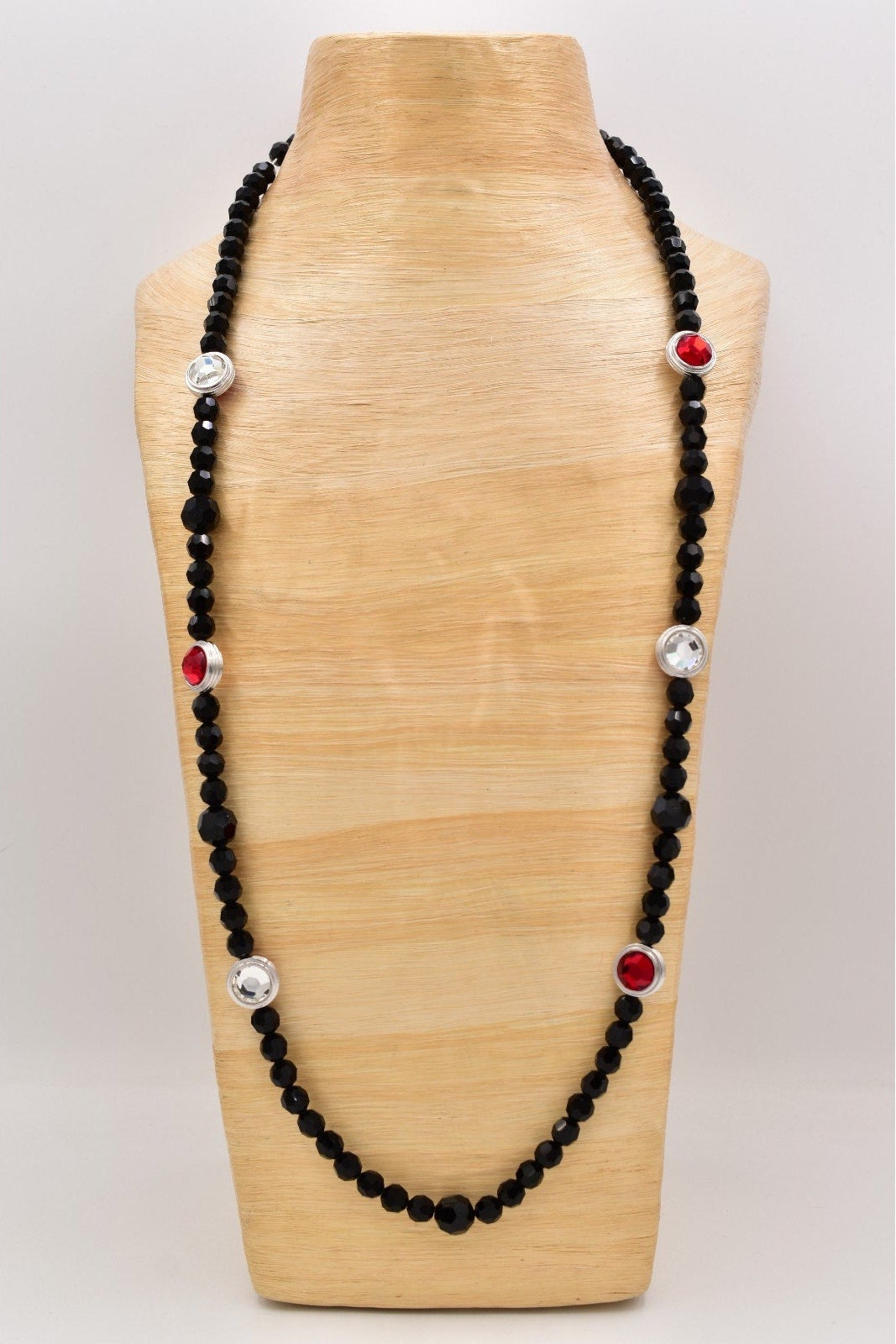Black beaded necklace with red and silver accents on a wooden mannequin bust.