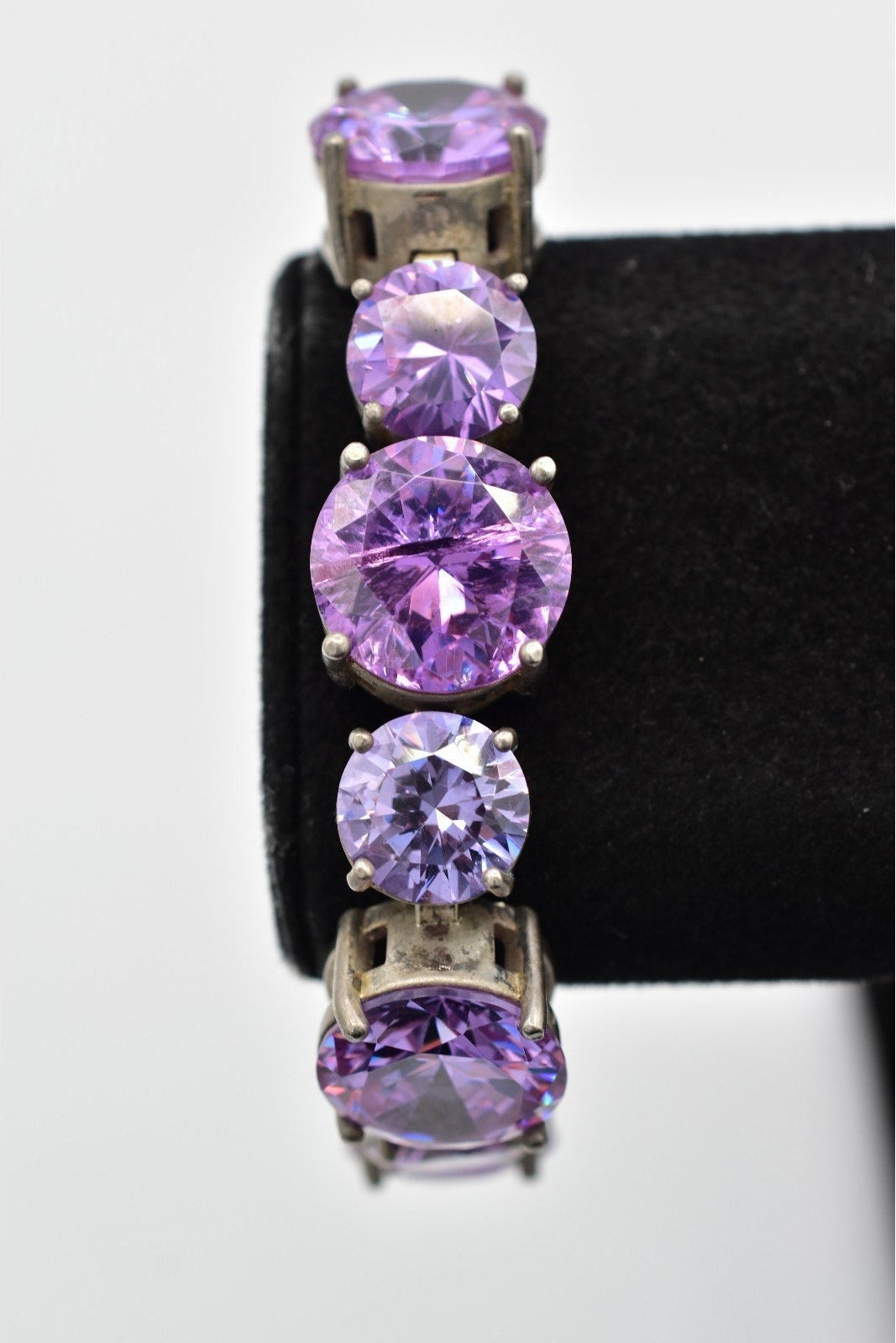 Purple gemstone earrings on a black stand against a white background