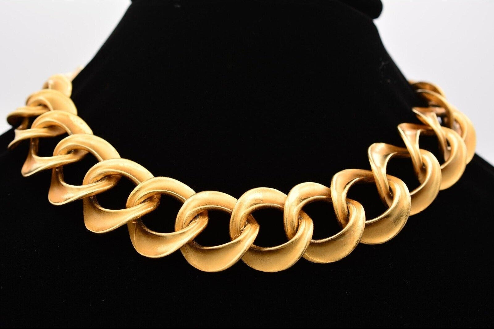 Gold chain necklace on a black mannequin with a white background