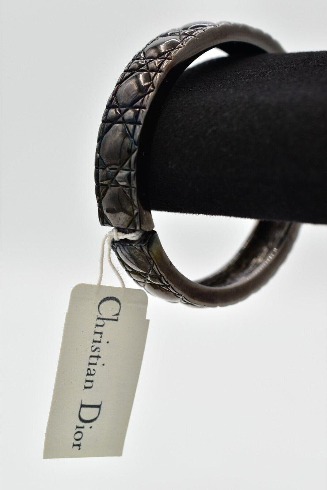 View of the tag on a vintage black metal quilted Christian Dior heavy bangle