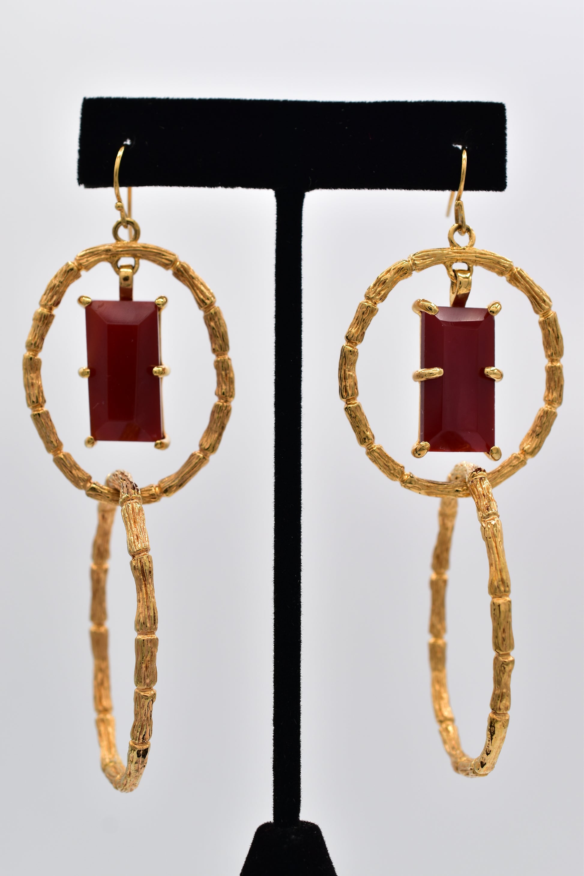 Pair of gold earrings with red gemstones on a white background