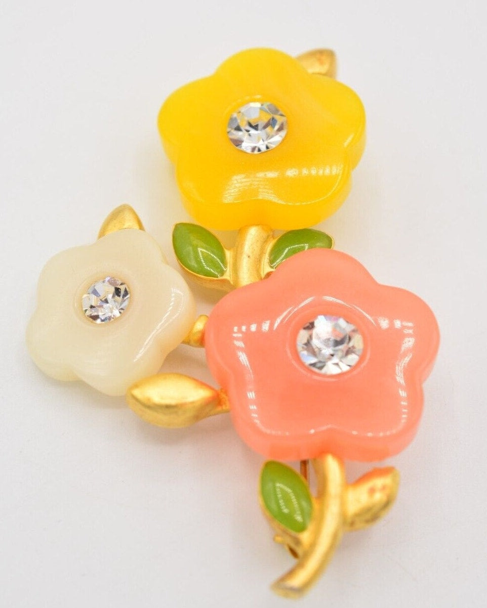 View of a vintage Givenchy brushed gold floral brooch with yellow, white, and pink colored acrylic petals with rhinestone crystals in the center on a white background