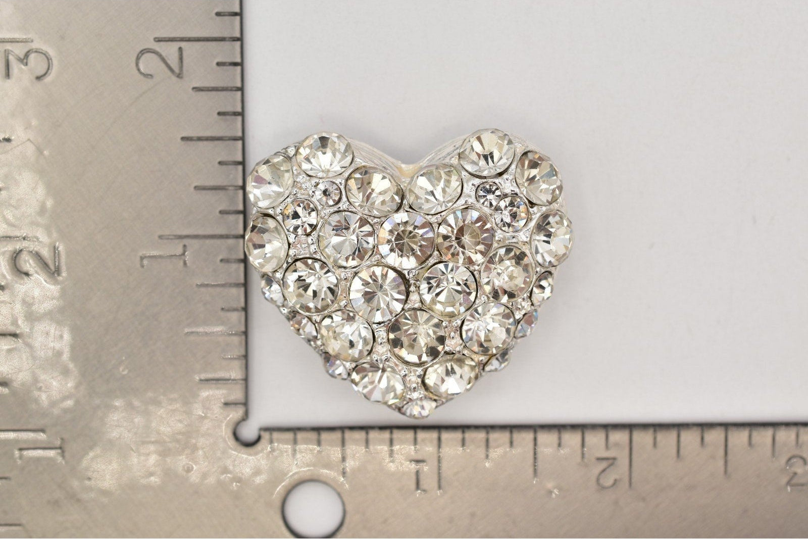 Heart-shaped decorative item with crystals on a ruler for scale