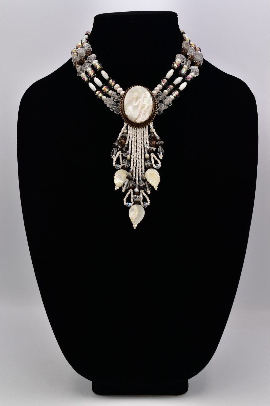 Decorative necklace on a black mannequin bust against a gray background